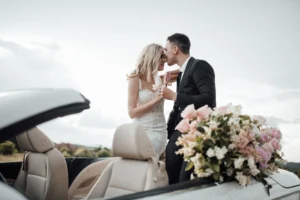 Bride and groom enjoying a convertible ride, showcasing a unique wedding transportation